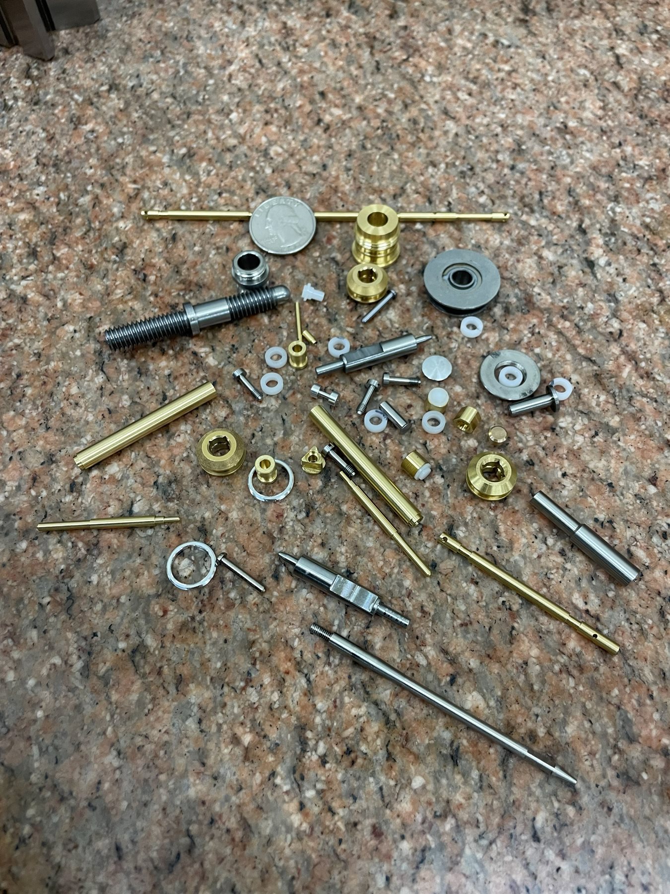 Tiny precision-machined parts with a coin for scale